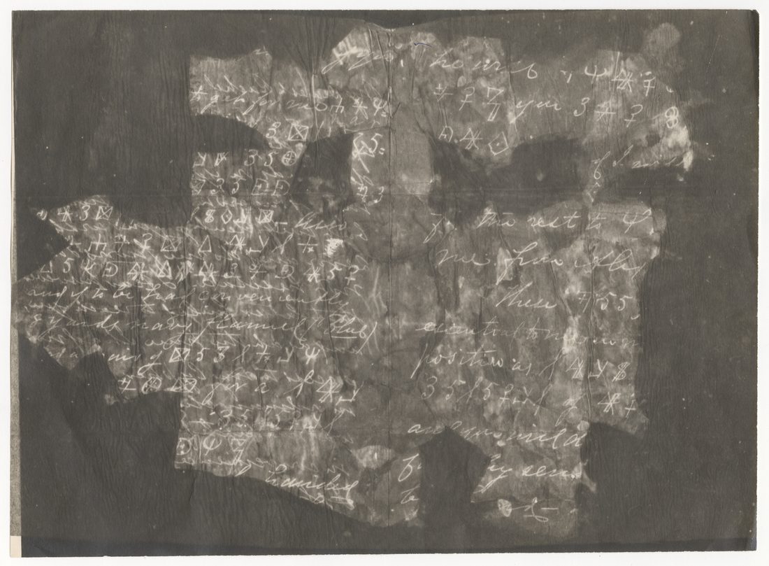 Photostat negative of burnt letter fragments pasted together, white writing on a dark ground